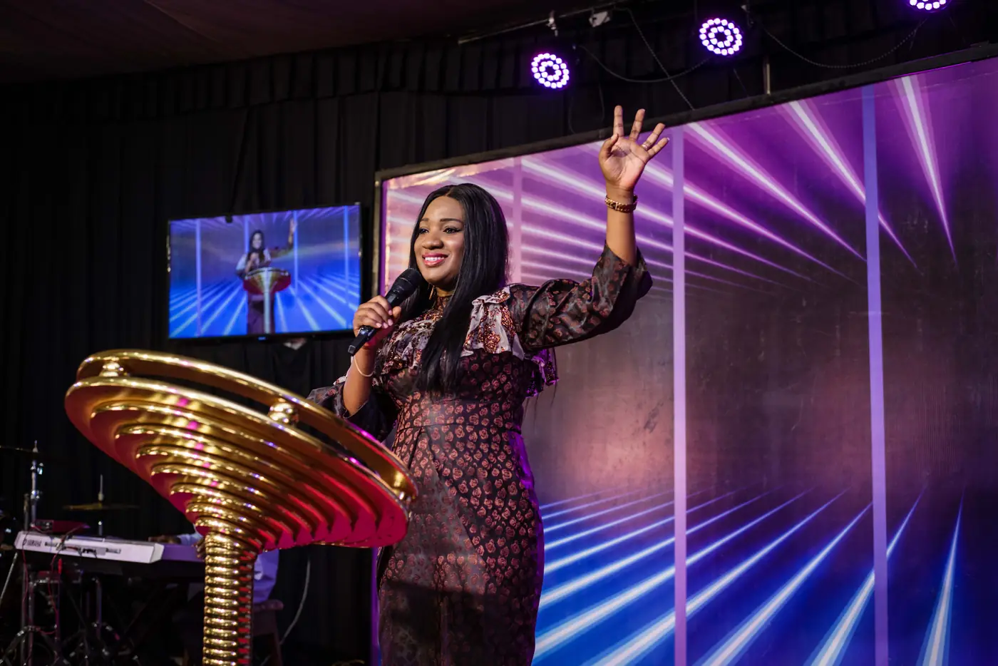 A minister on stage under purple lights