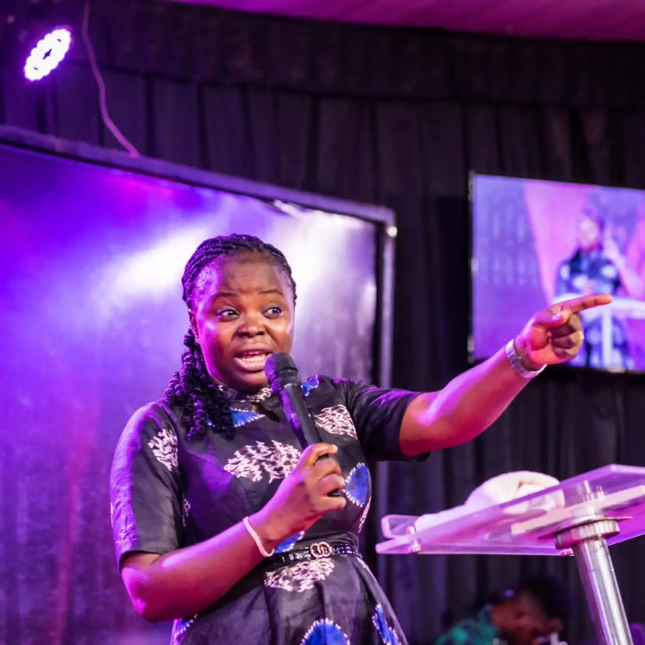 A minister preaching on a purple-lit stage