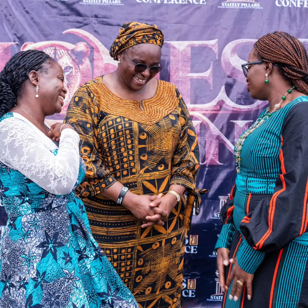Three women laughing together at the conference backdrop