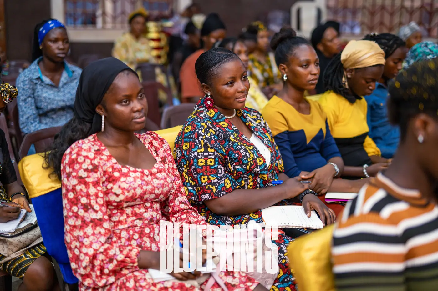 Attendees seated, listening and taking notes